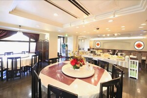 Un restaurante con mesas redondas, sillas y una zona de bufé.