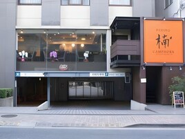 A modern building with a glass entrance, a sign for a dining area, and a parking sign.