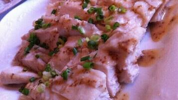 A close-up of a dish with sliced meat and green onions.