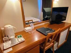 A hotel room desk with a coffee maker, a tray with a mug and tea, a notebook, and a remote control. - R Hotel Inn Kitakyushu Airport (KANDA)