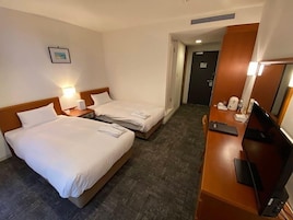 A hotel room with two beds, a desk with a computer, a TV, and a picture on the wall.