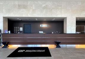 A reception area with a marble wall, a reception desk, and a sign for the BluePort Hotel.
