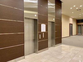 A modern elevator area with wood paneling and a tiled floor.