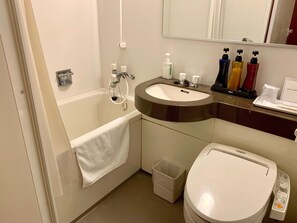Un baño con bañera, lavabo, inodoro y artículos de aseo sobre el mostrador.