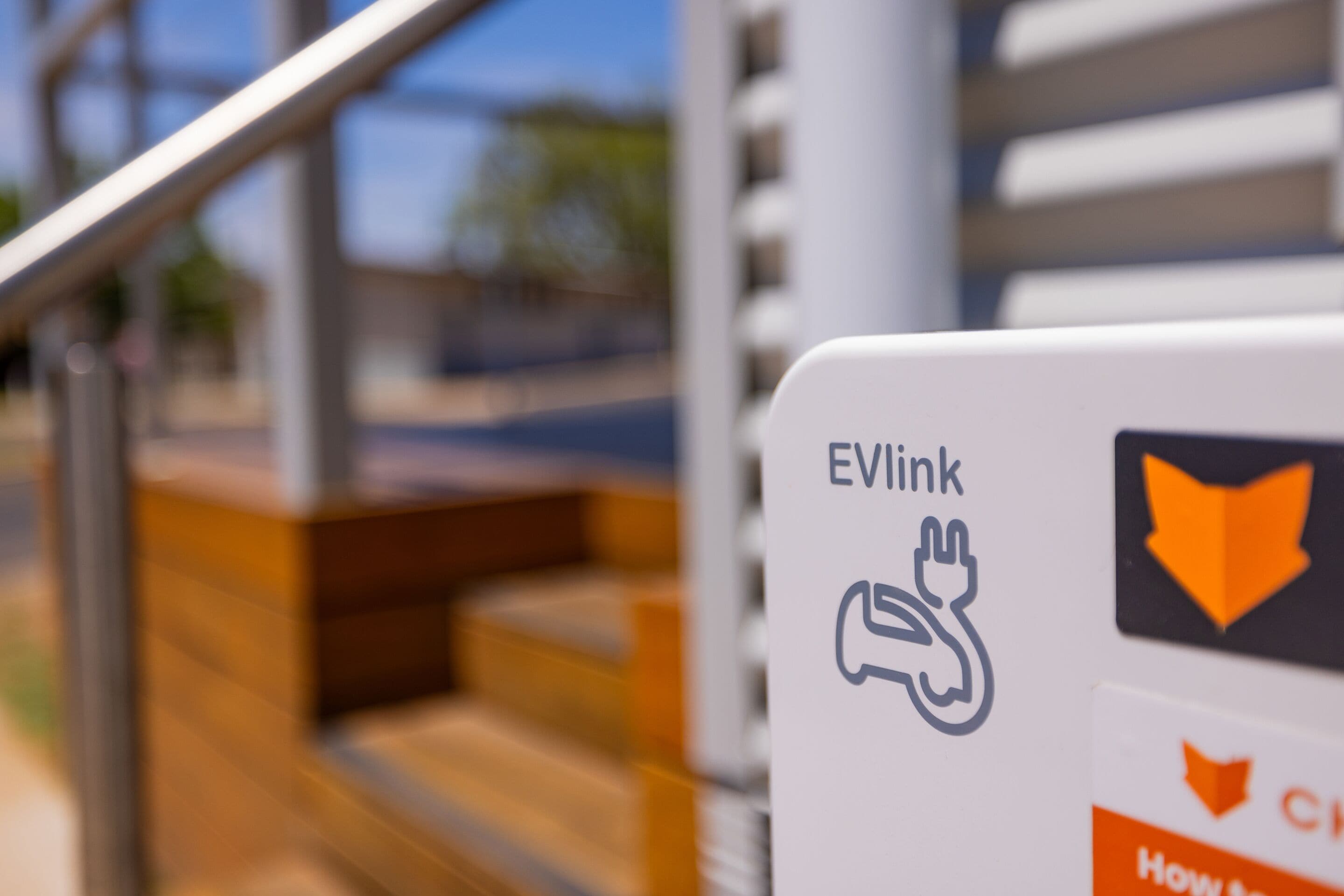Una señal con el logotipo de EVLink y un símbolo de enchufe, que indica la disponibilidad de carga para vehículos eléctricos.