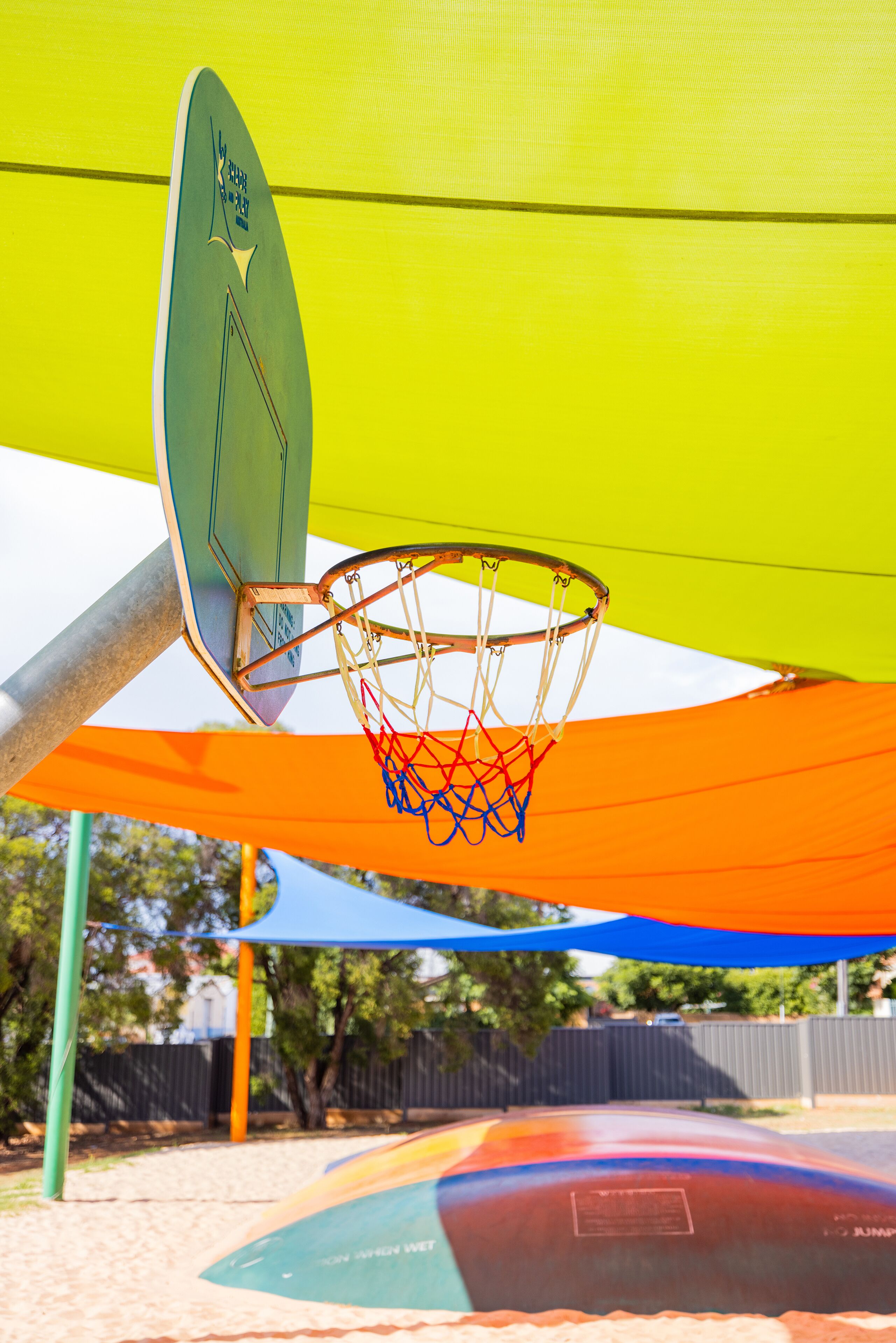 Ein Basketballkorb mit Netz, befestigt an einem Pfosten, und ein farbenfroher Baldachin darüber.