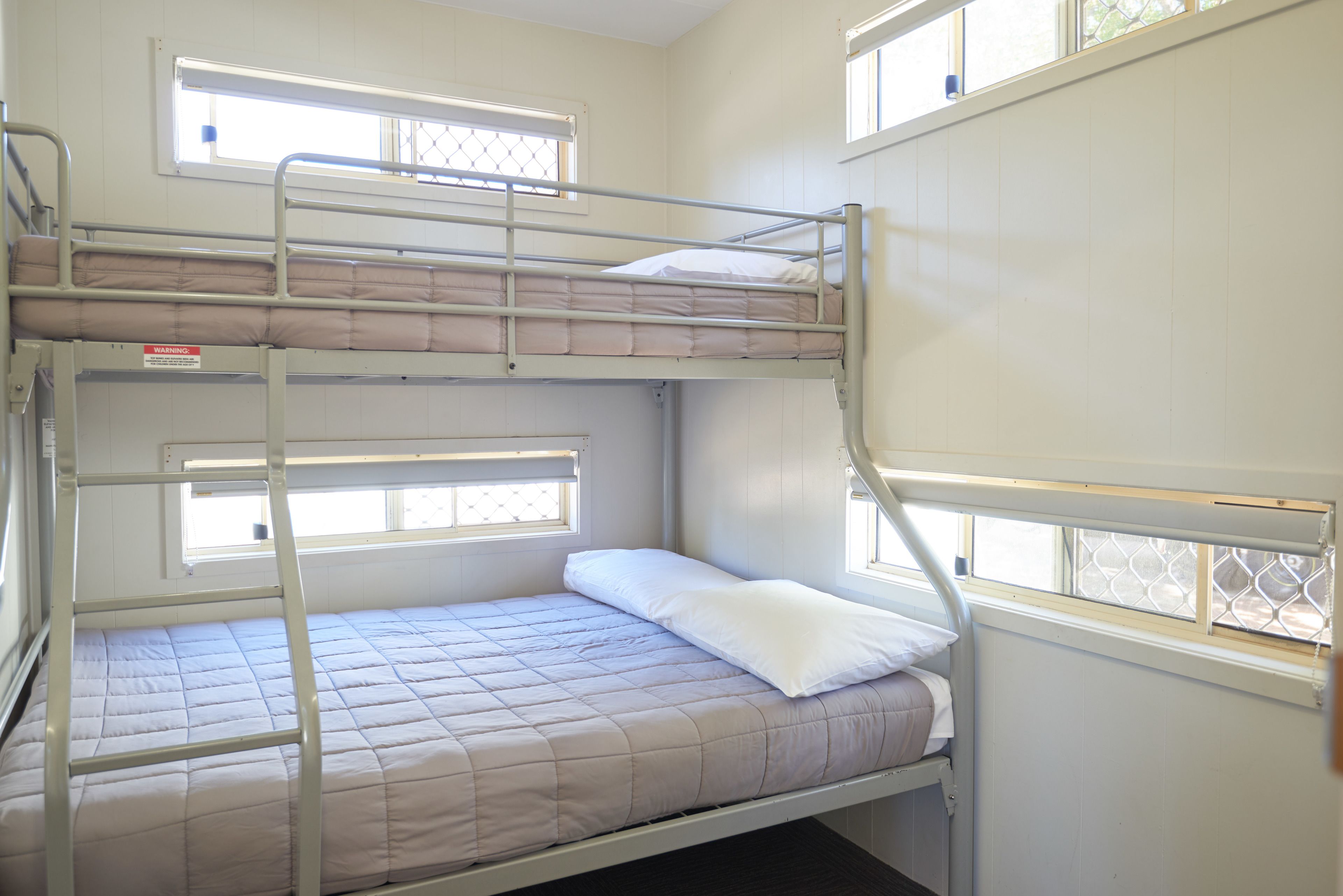 A bunk bed room with a window, a ladder, and a mattress.