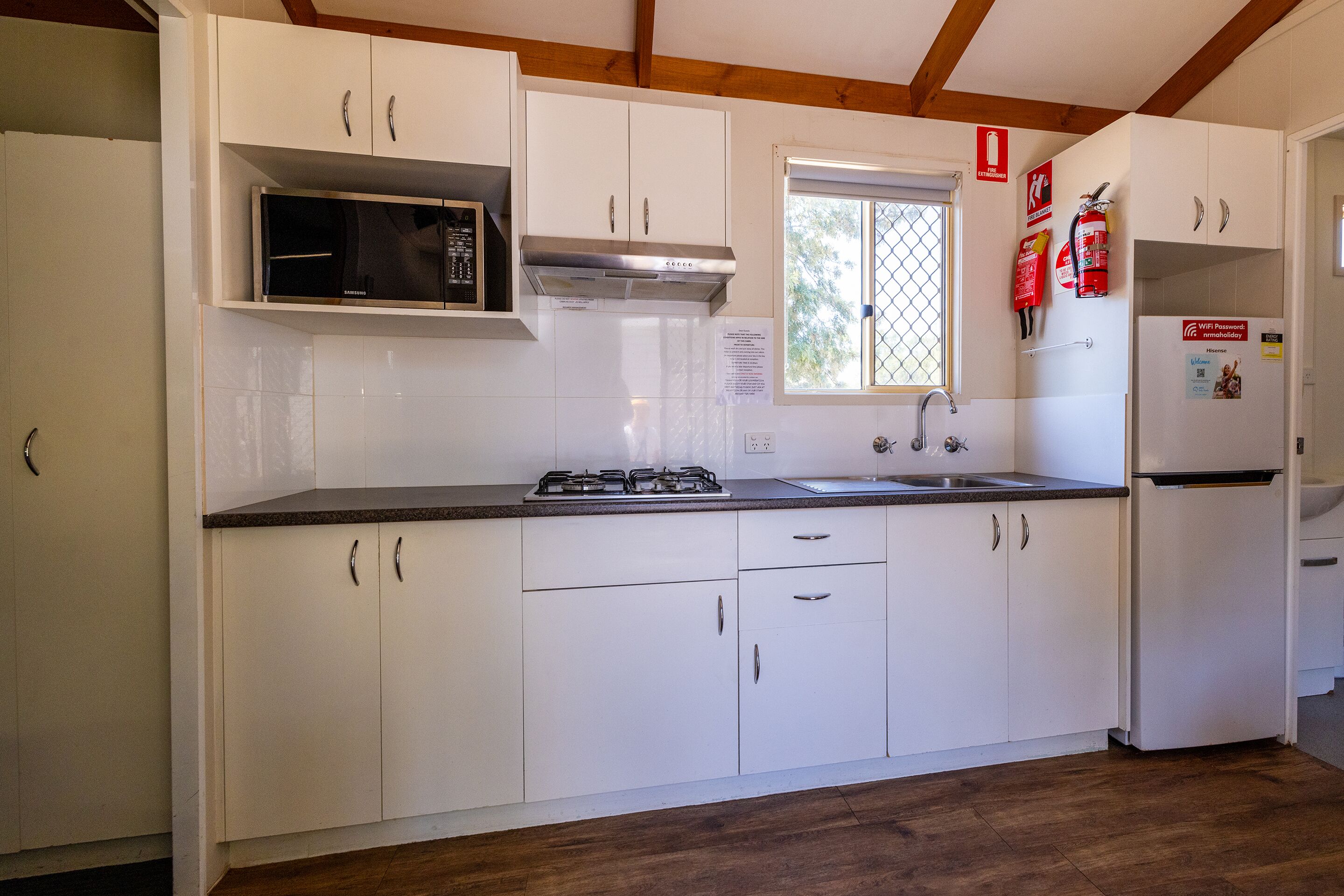 Une cuisine moderne avec des meubles blancs, un four à micro-ondes, une cuisinière à gaz et un réfrigérateur.