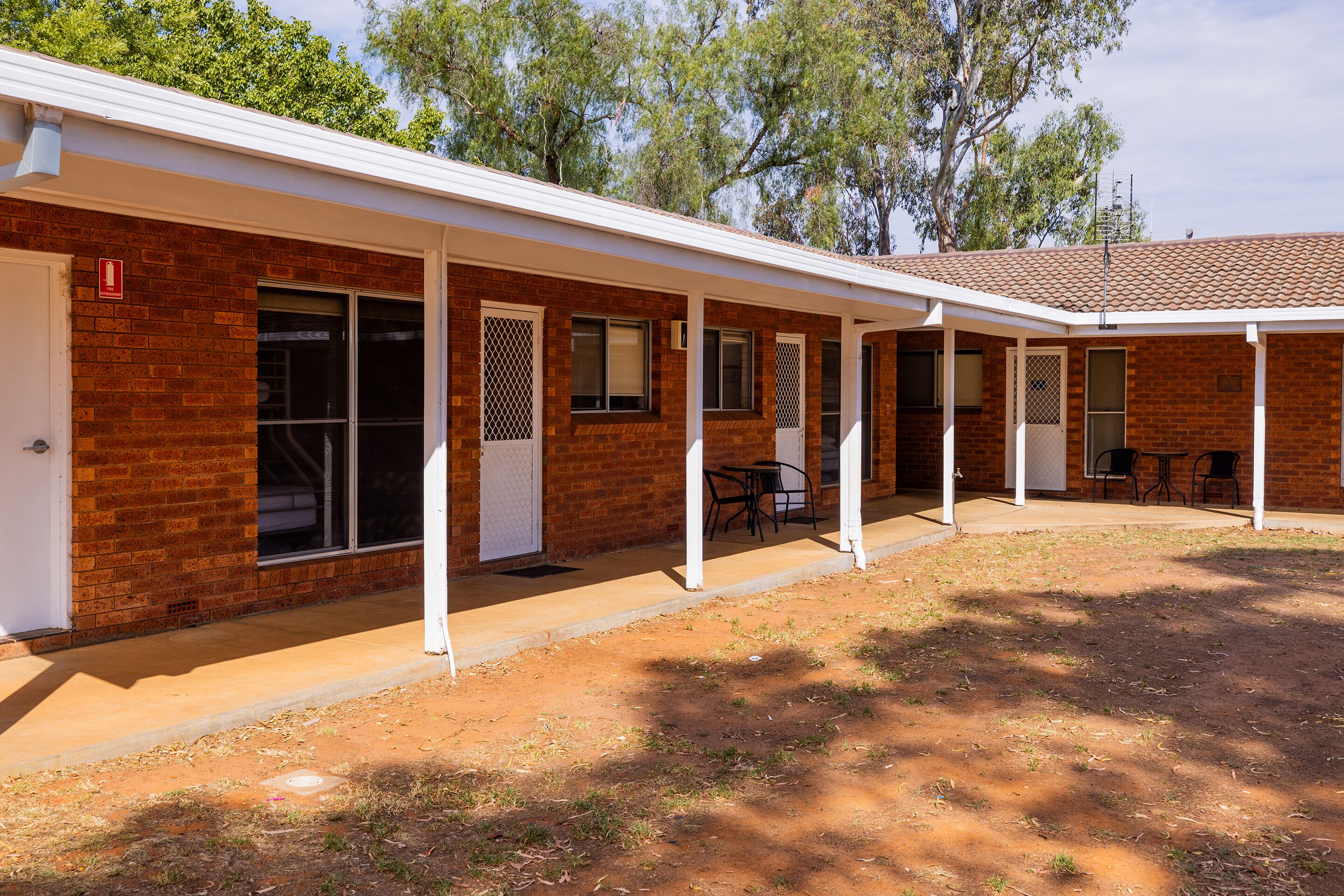 A brick building with a covered patio area, including a seating area with chairs and tables.
