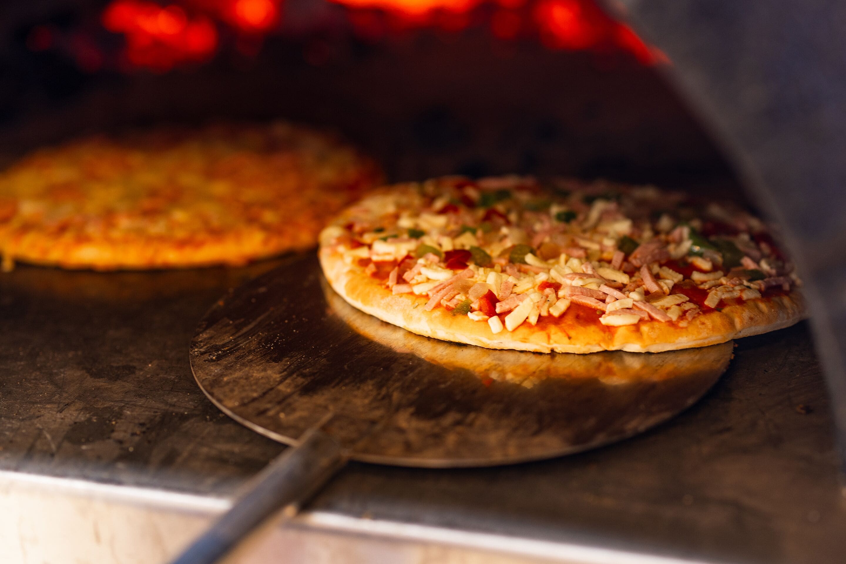 Two pizzas in a wood-fired oven.