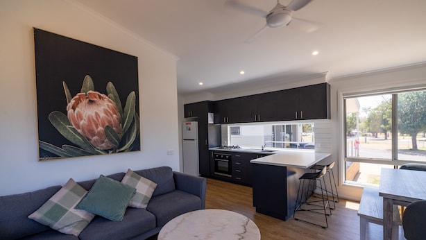 Un salon moderne avec un canapé gris, une table basse en marbre et un grand tableau représentant une fleur.