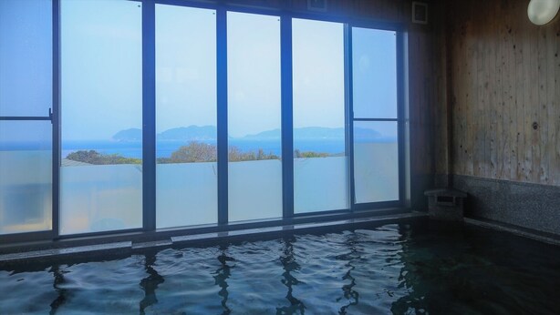 A room with a large window overlooking a body of water and distant land. - Kokumin Syukusya Hadomisaki (Karatsu)