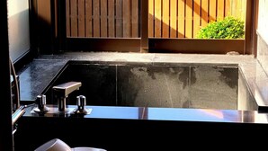 A bathroom with a sink, toilet, and a window with a view of a wooden fence and greenery. - Kokumin Syukusya Hadomisaki (Karatsu)