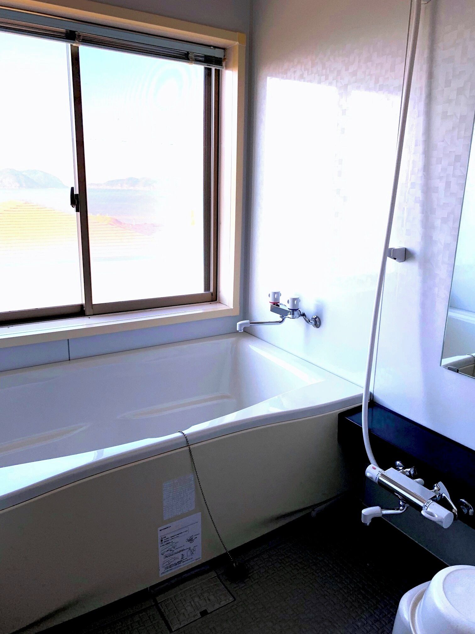 A bathroom with a bathtub, a window, and a toilet.
