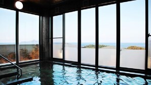 An indoor swimming pool with large windows and a view of a body of water. - Kokumin Syukusya Hadomisaki (Karatsu)