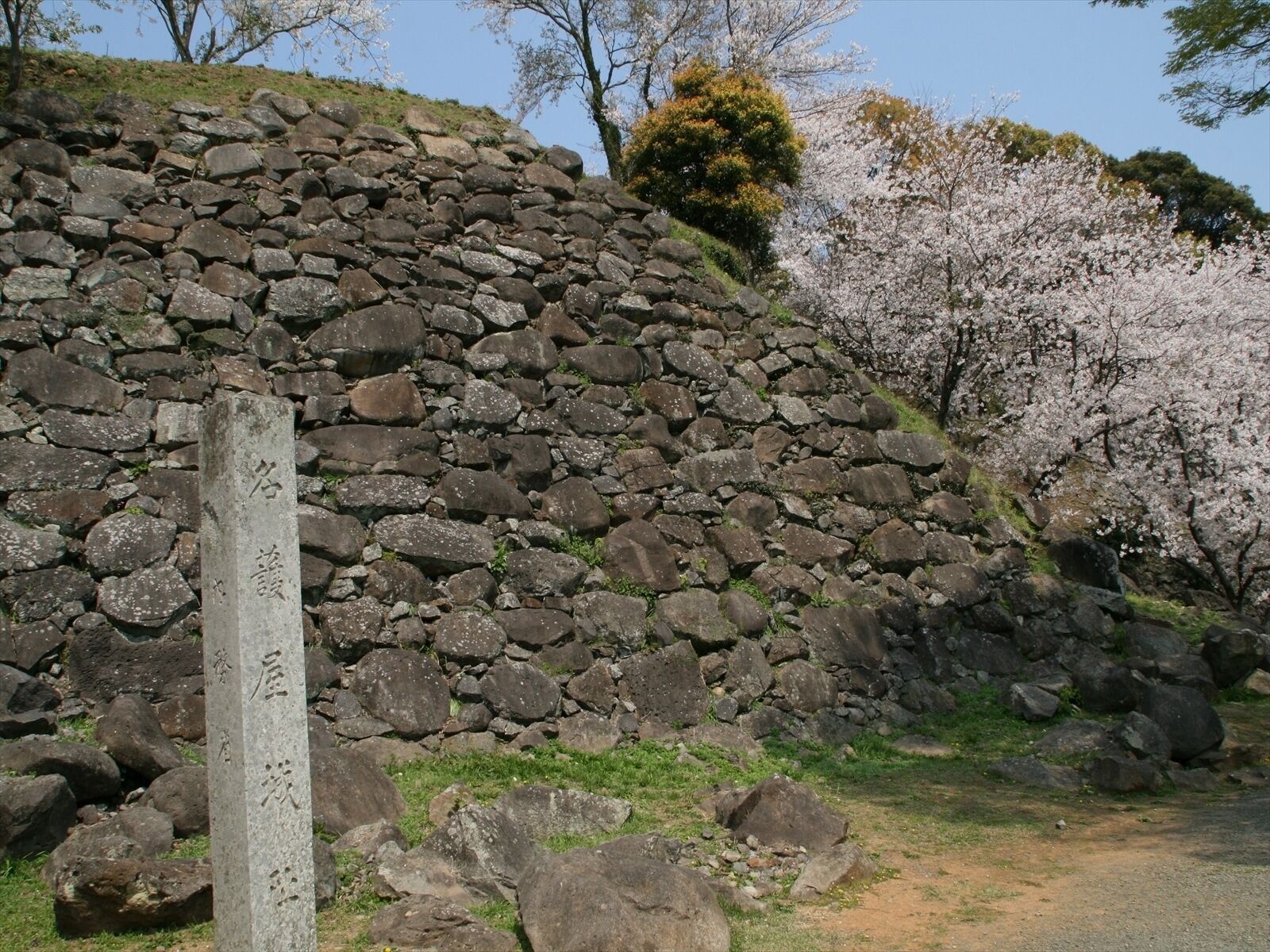 A stone wall with a wooden post in the foreground.