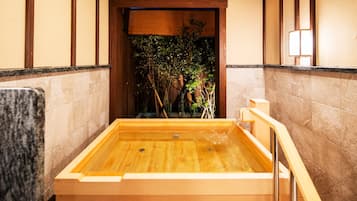 A wooden hot tub with a view of a bamboo garden.