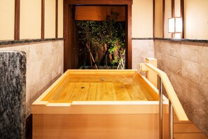 Een houten jacuzzi met uitzicht op een bamboebos.