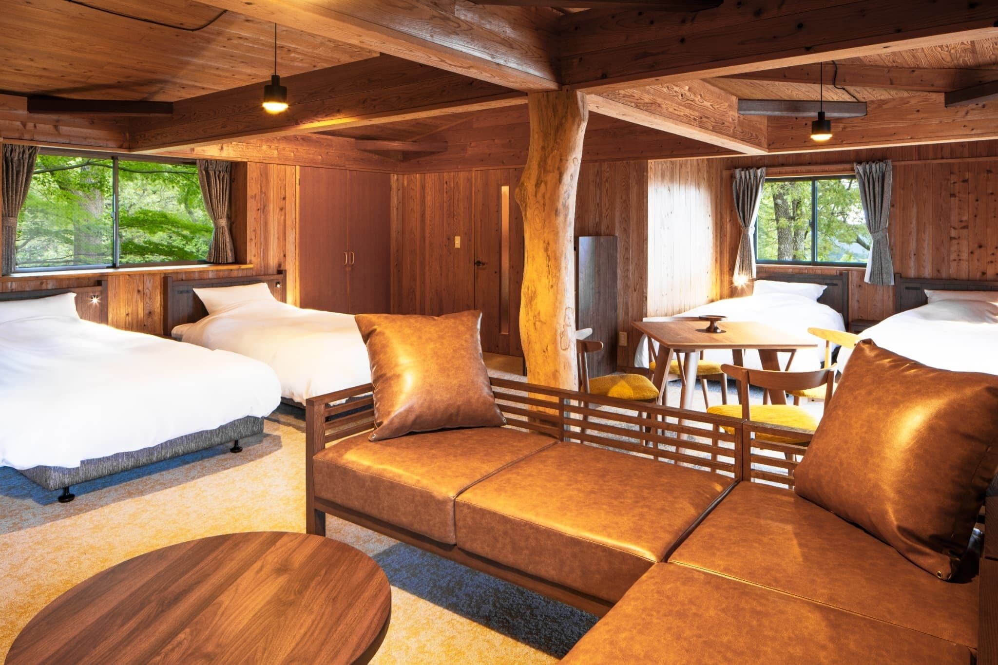 L’intérieur d’une cabine comprenant un canapé, deux lits, une table à manger et une grande fenêtre.
