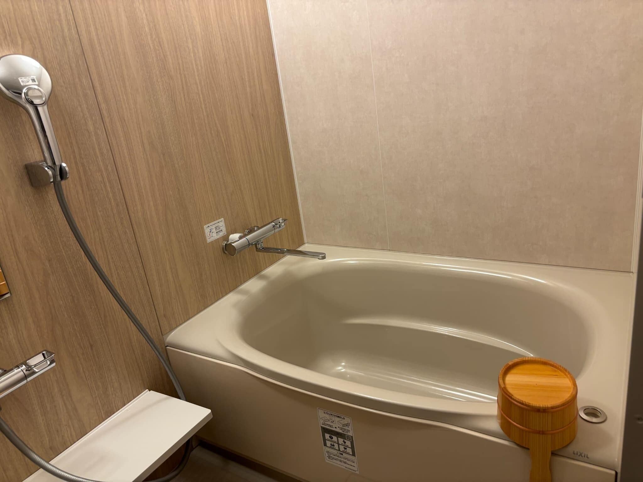 Un baño con bañera, ducha y asiento de bidé de madera.
