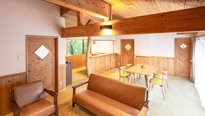 Een kamer met een houten plafond, een bank, een tafel en stoelen.