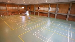 En indendørs badmintonhal med flere baner markeret i gult og hvidt.