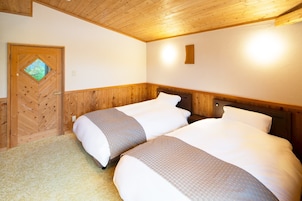 Habitación con dos camas, cabeceros de madera, una puerta de madera con ventana y suelo cubierto de alfombra.