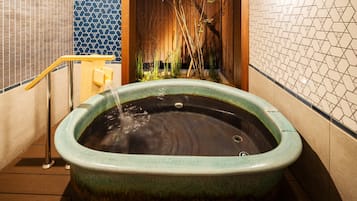 A spa area with a hot tub, wooden flooring, and tiled walls.