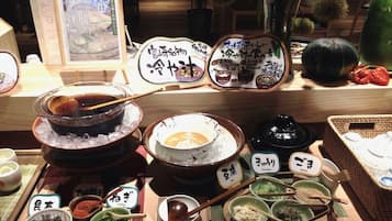 A variety of food items and condiments displayed on a table, including bowls of soup and dishes with labels indicating ingredients like cucumber and sesame.