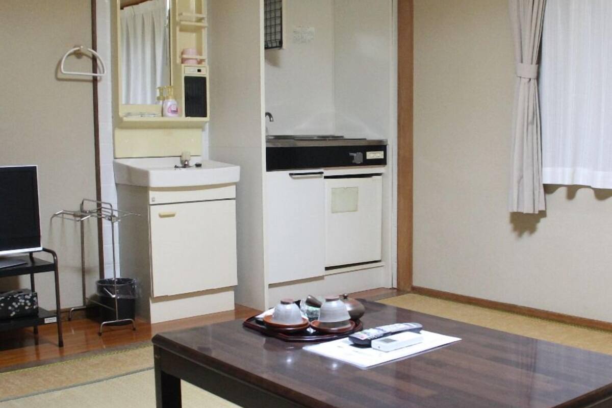 Une chambre d’hôtel avec une table en bois, un téléviseur, un lavabo et une armoire.