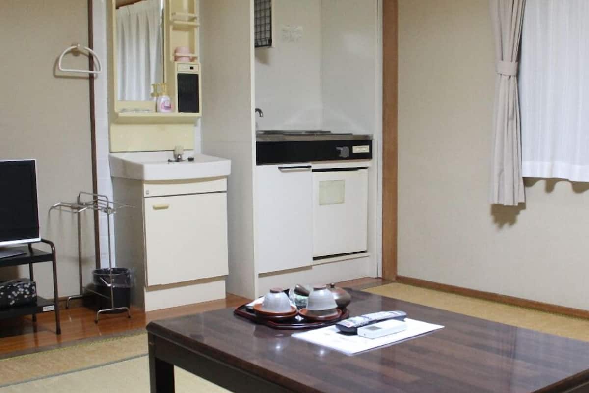Ein Hotelzimmer mit einem Holztisch, einem Fernseher, einem Waschbecken und einem Kleiderschrank.