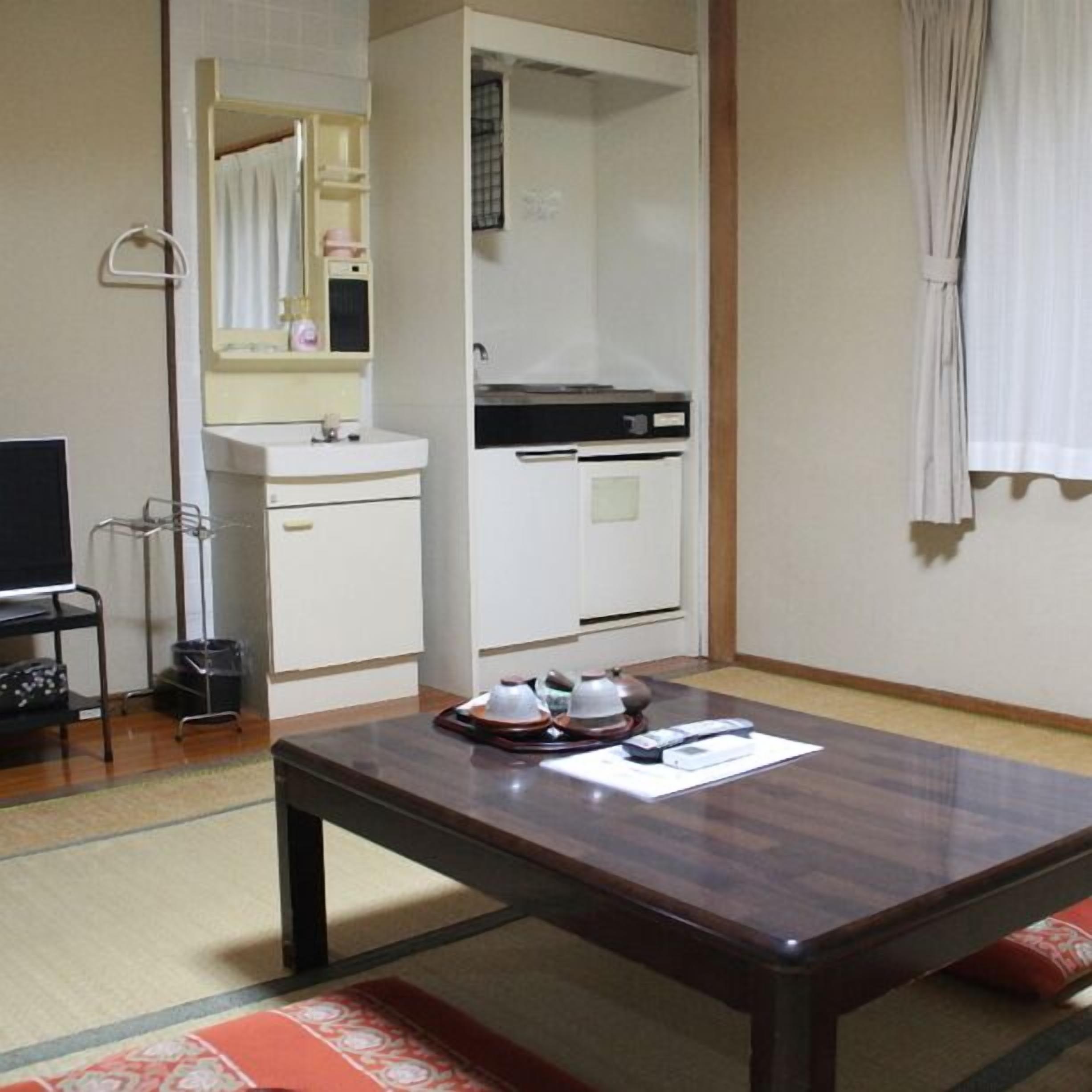 Une pièce avec une table en bois, un lavabo blanc, un miroir et une fenêtre avec des rideaux.