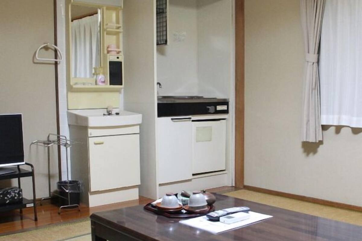 Une pièce avec une table en bois, un lavabo blanc, un miroir et une fenêtre avec des rideaux.