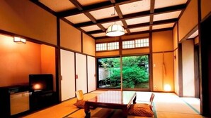 Una habitación japonesa tradicional con suelo de tatami, una mesa baja y puertas correderas.