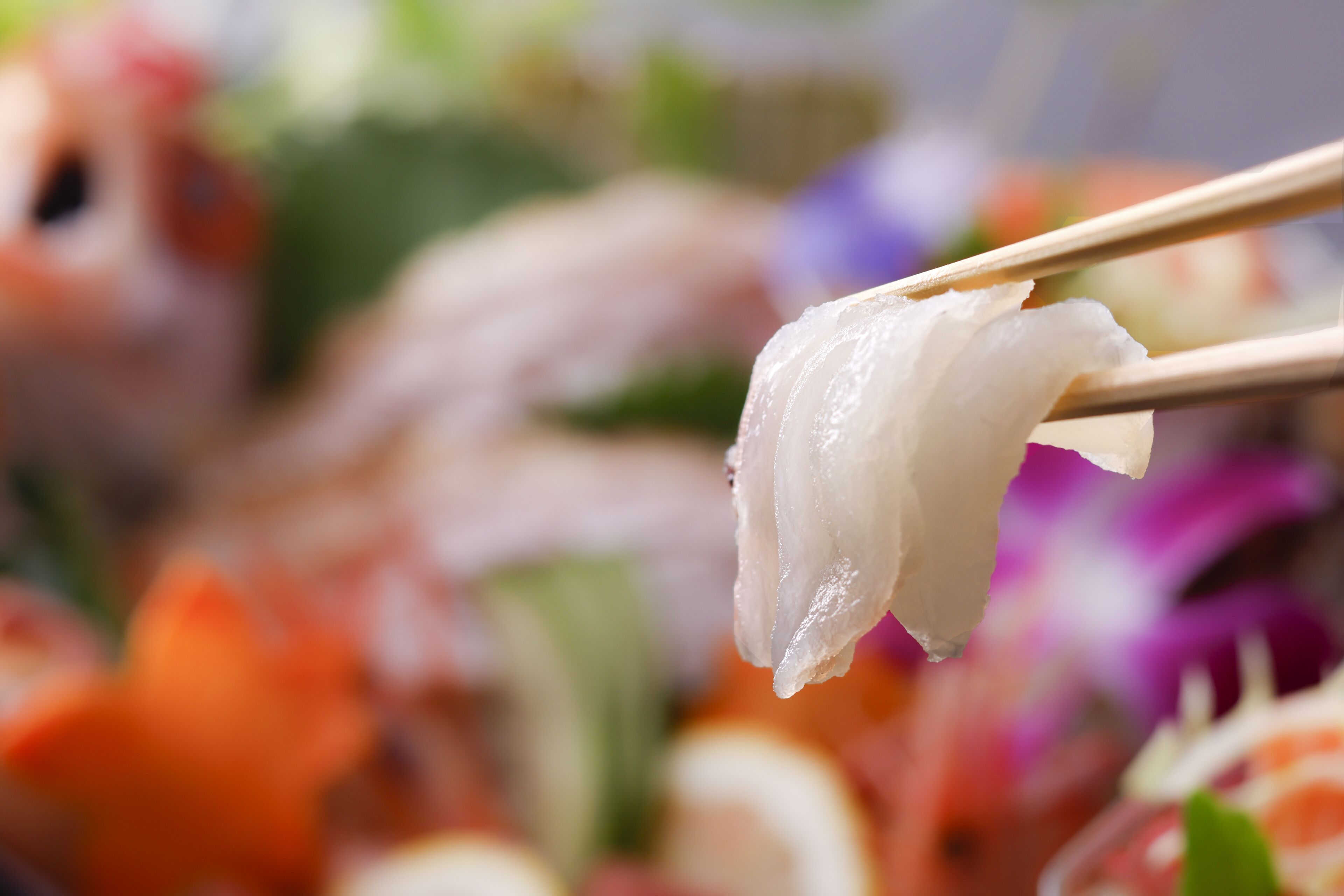A close-up of sushi being held by chopsticks.