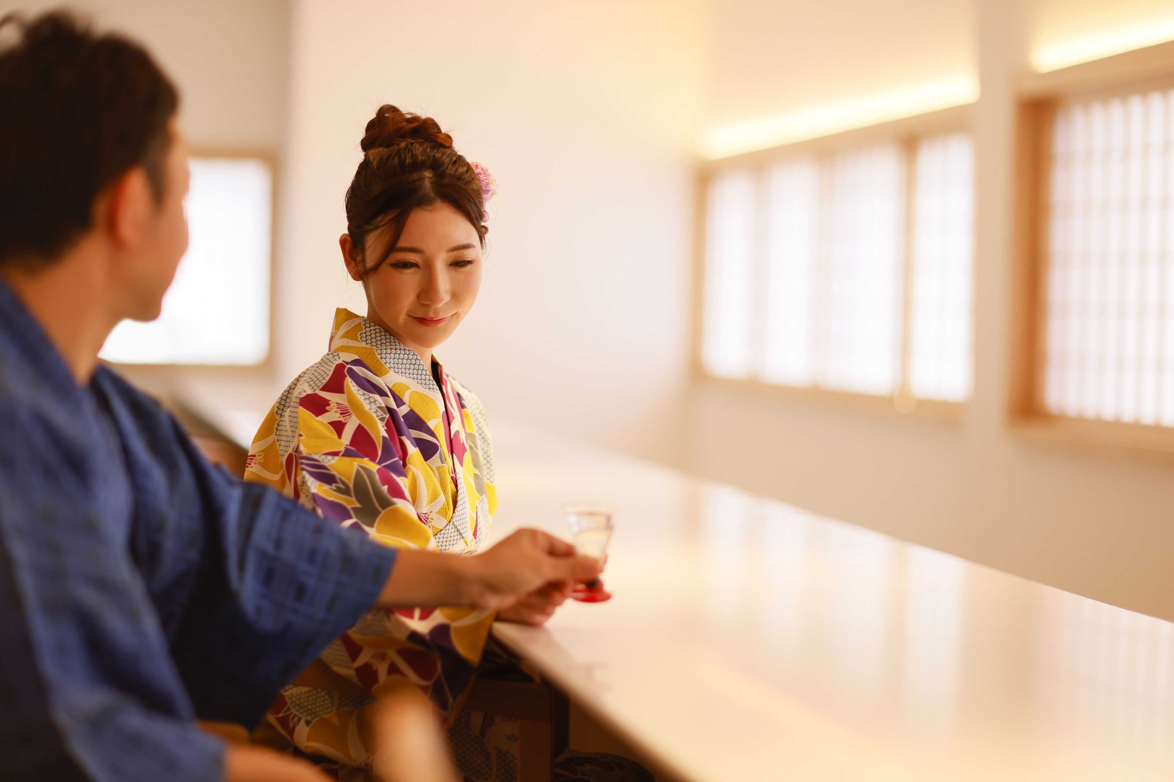 A person in traditional attire sitting at a table with a drink.