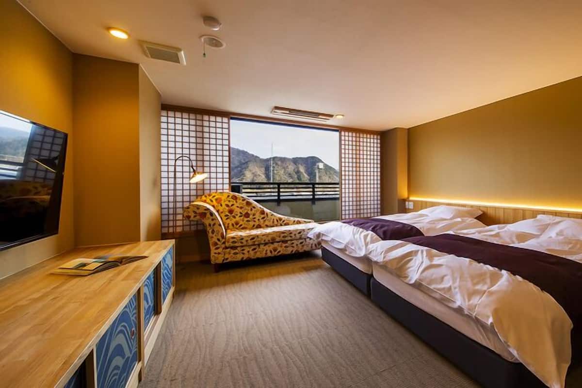 Ein Hotelzimmer mit Bett, Sofa, Fernseher und Blick auf Berge.
