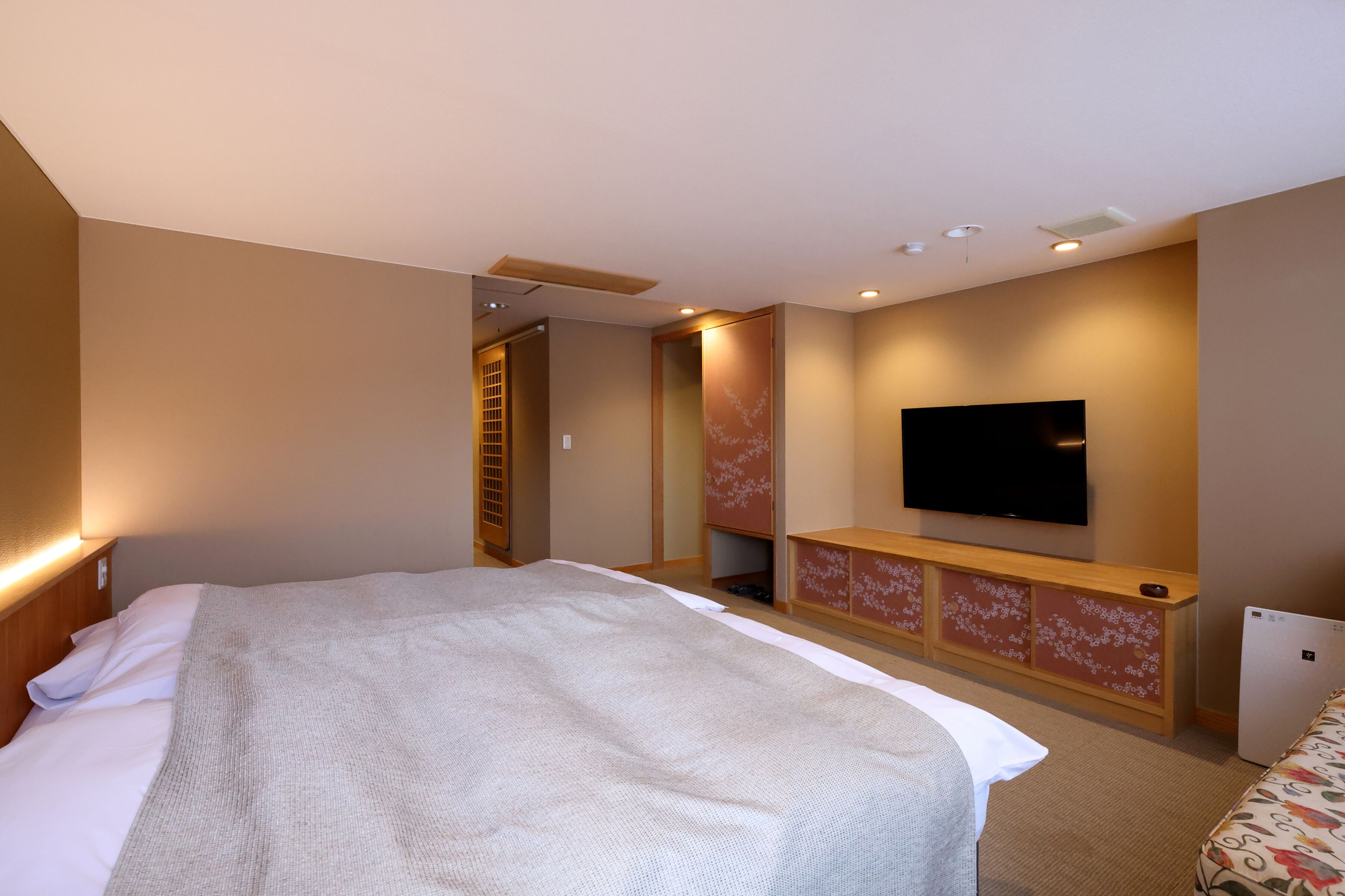 Habitación de hotel con una cama grande, un televisor de pantalla plana en la pared y un refrigerador pequeño.