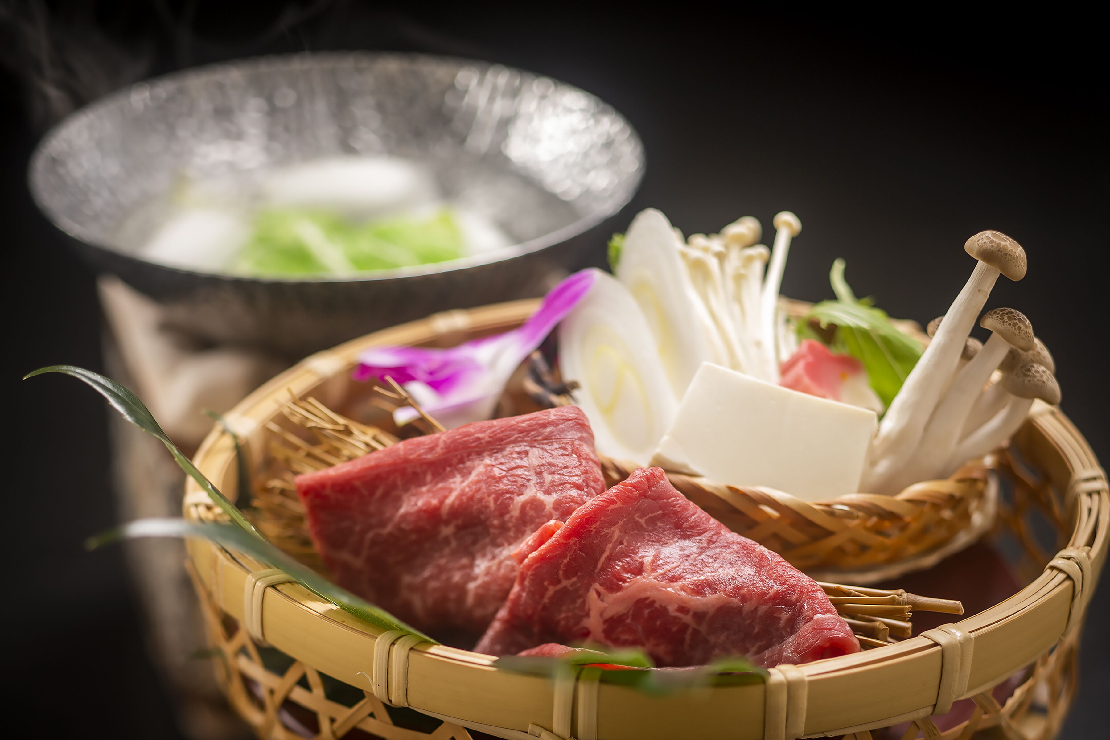A basket with raw meat, mushrooms, and vegetables, possibly for a meal.