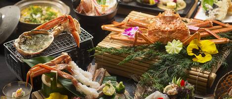 A variety of seafood dishes, including crab legs and shrimp, arranged on a table with decorative elements like flowers and bamboo.