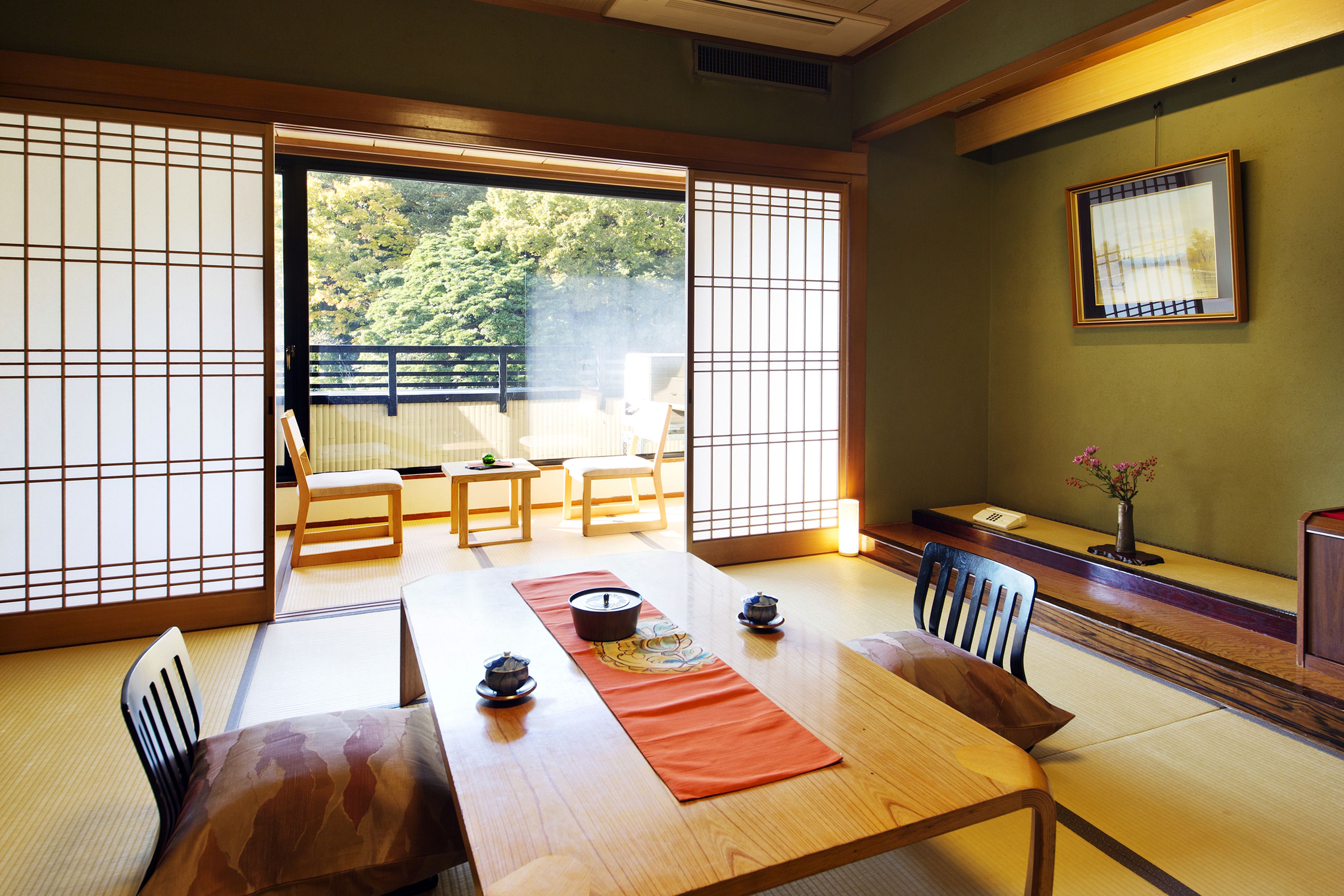 Une pièce de style japonais traditionnel, avec un sol recouvert de tatamis, une petite table sur laquelle est disposé un service à thé, et des portes coulissantes donnant sur un balcon extérieur.
