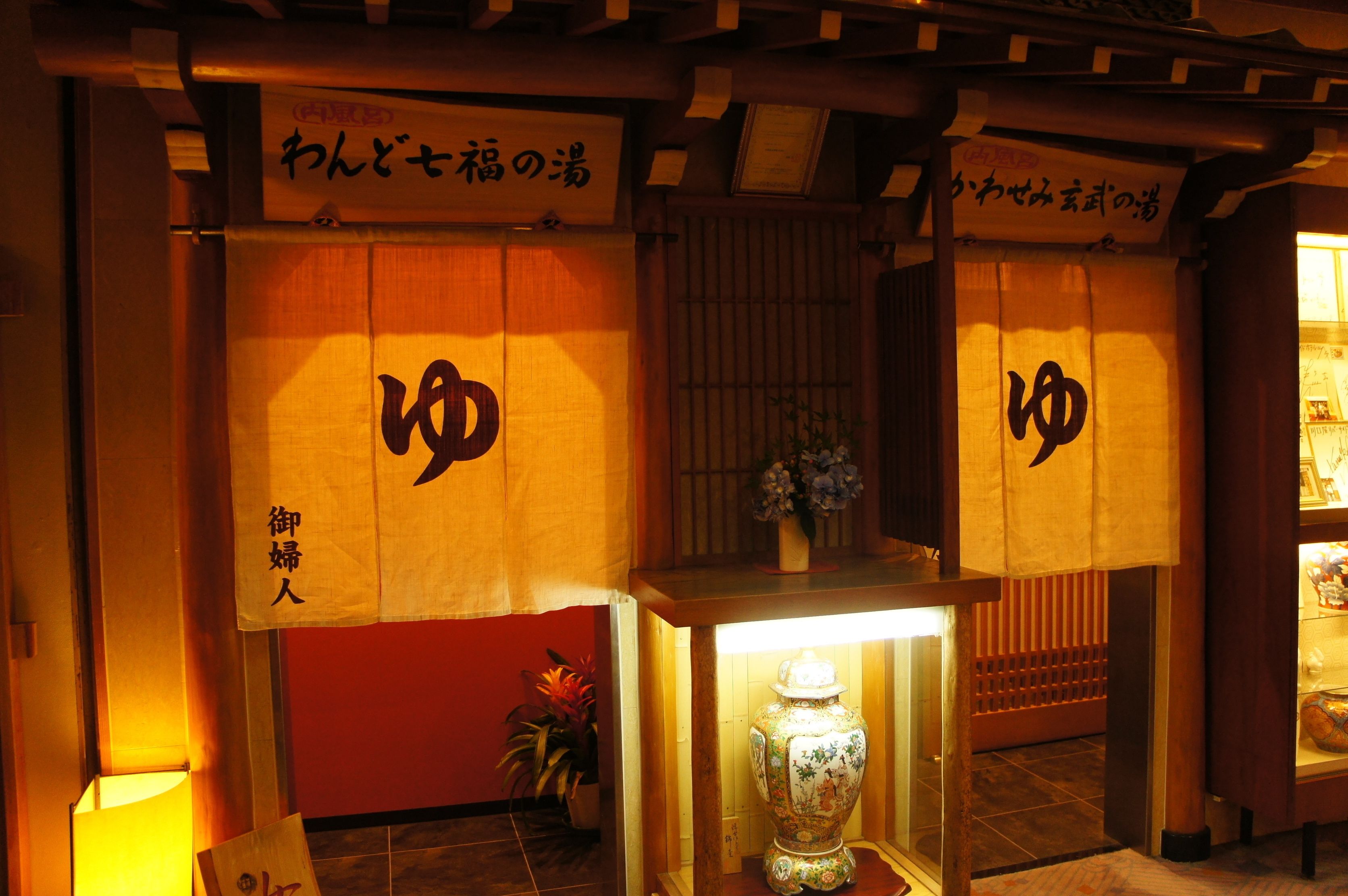 A traditional Japanese establishment with tatami mat flooring, a wooden reception desk, and a vase with flowers.