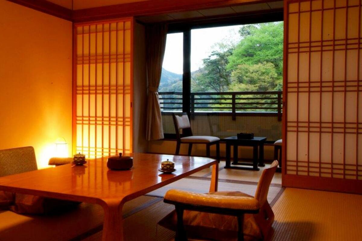 Ein traditioneller japanischer Raum mit Tatami-Böden, einem niedrigen Tisch und verschiebbaren Türen.