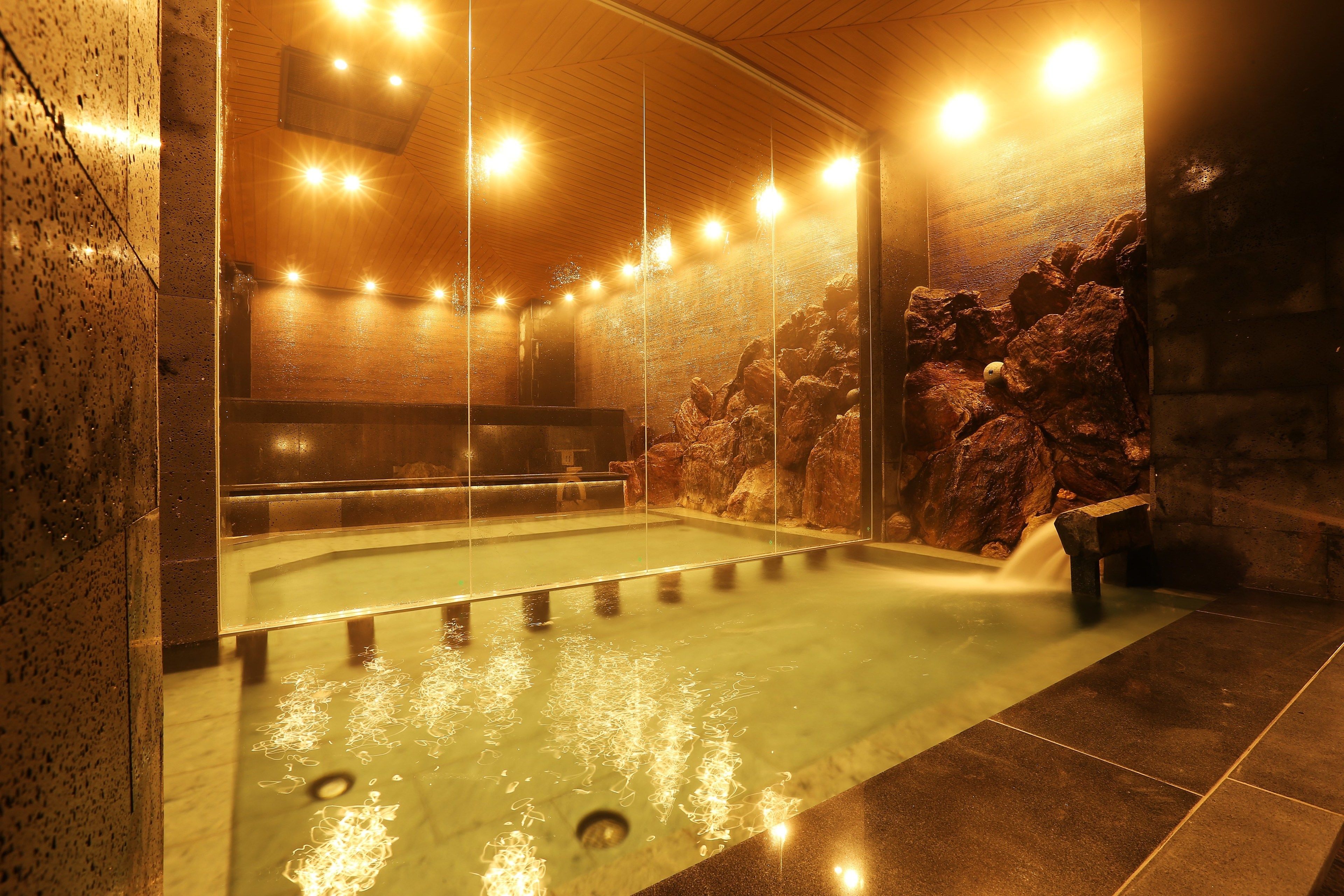 A spa area with a hot tub, stone walls, and a wooden ceiling.