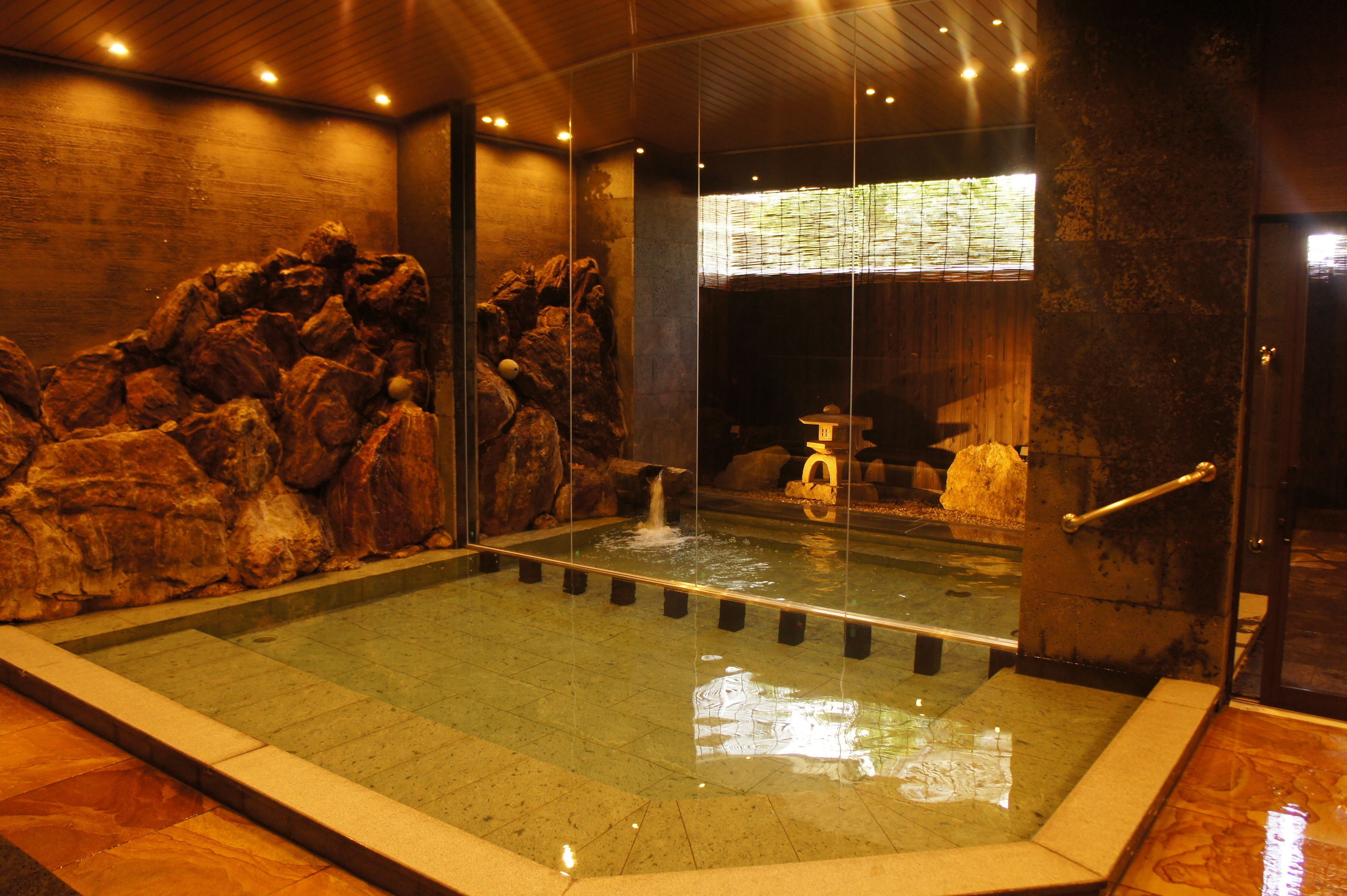 A large indoor pool with clear water, surrounded by rock formations and a glass barrier.