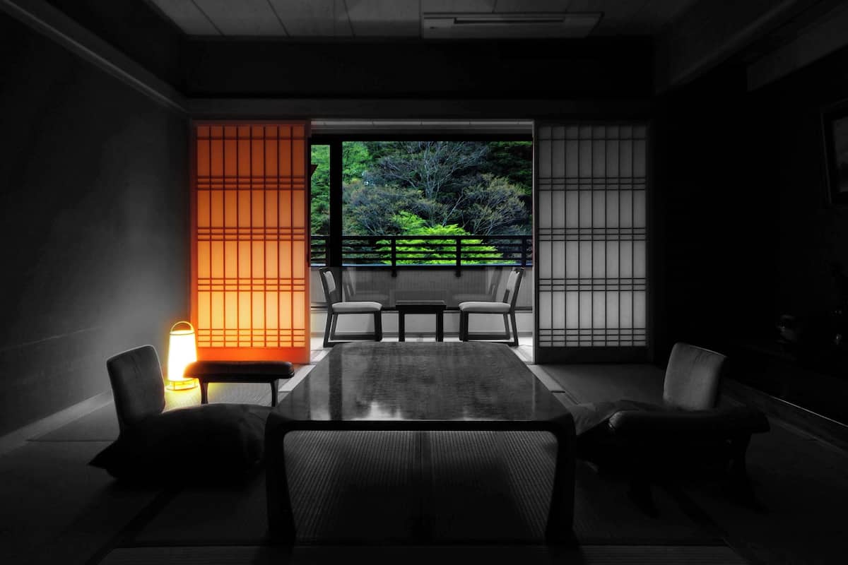 Ein traditioneller japanischer Raum mit Tatami-Boden, einem niedrigen Tisch und Stühlen.