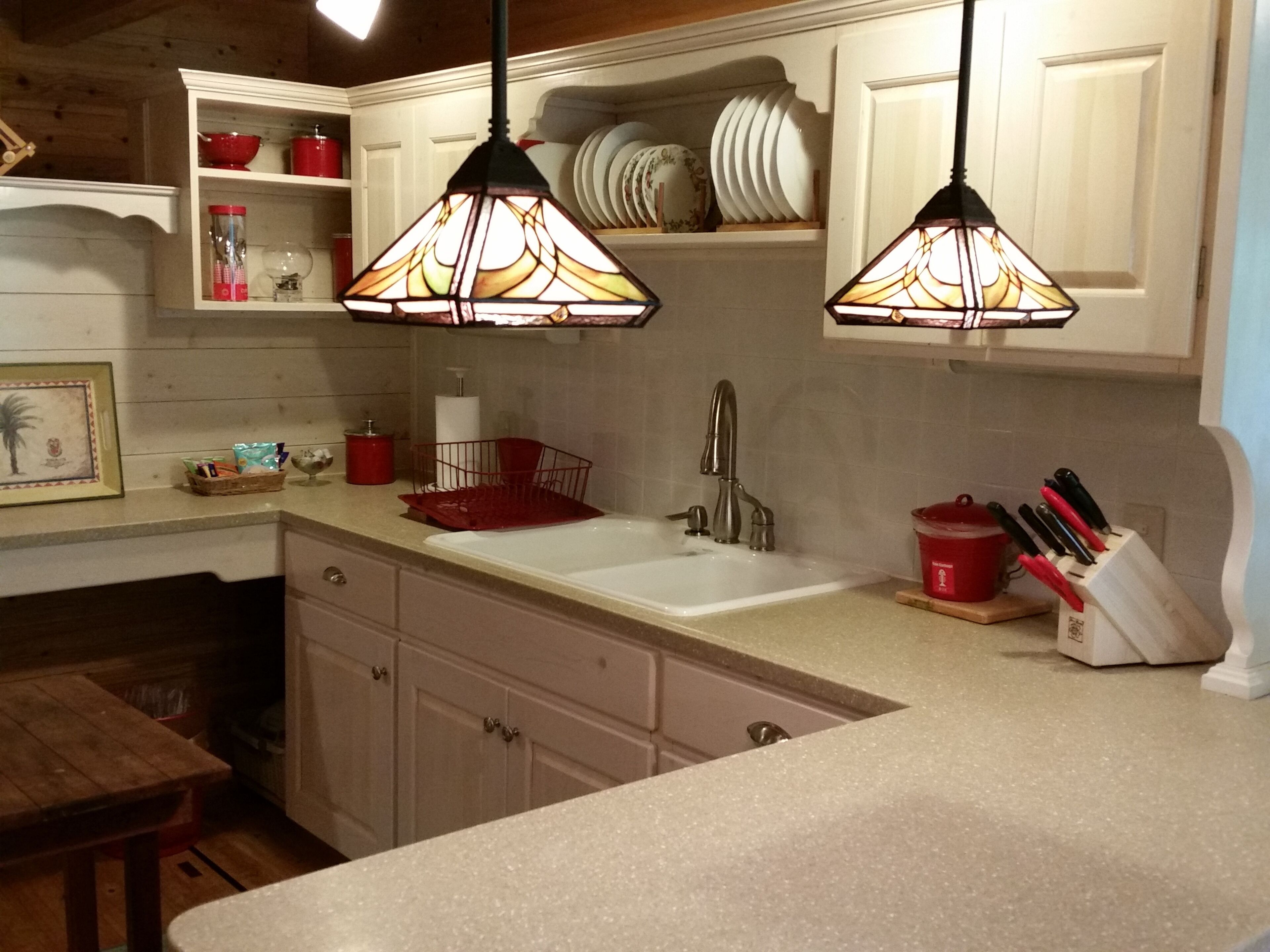A kitchen with white cabinets, a sink, and two pendant lights.