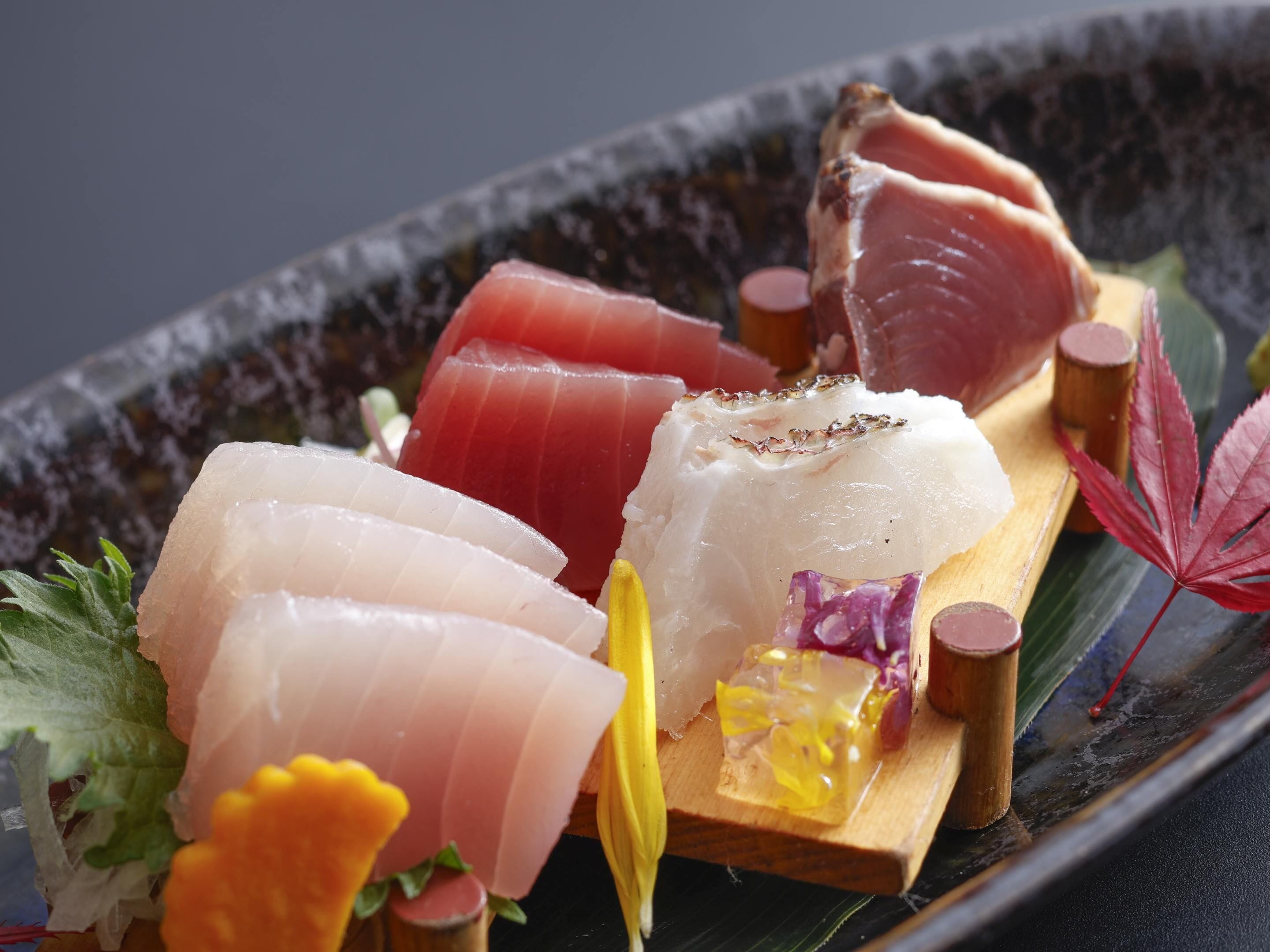 A sushi platter with various types of fish and garnishes.