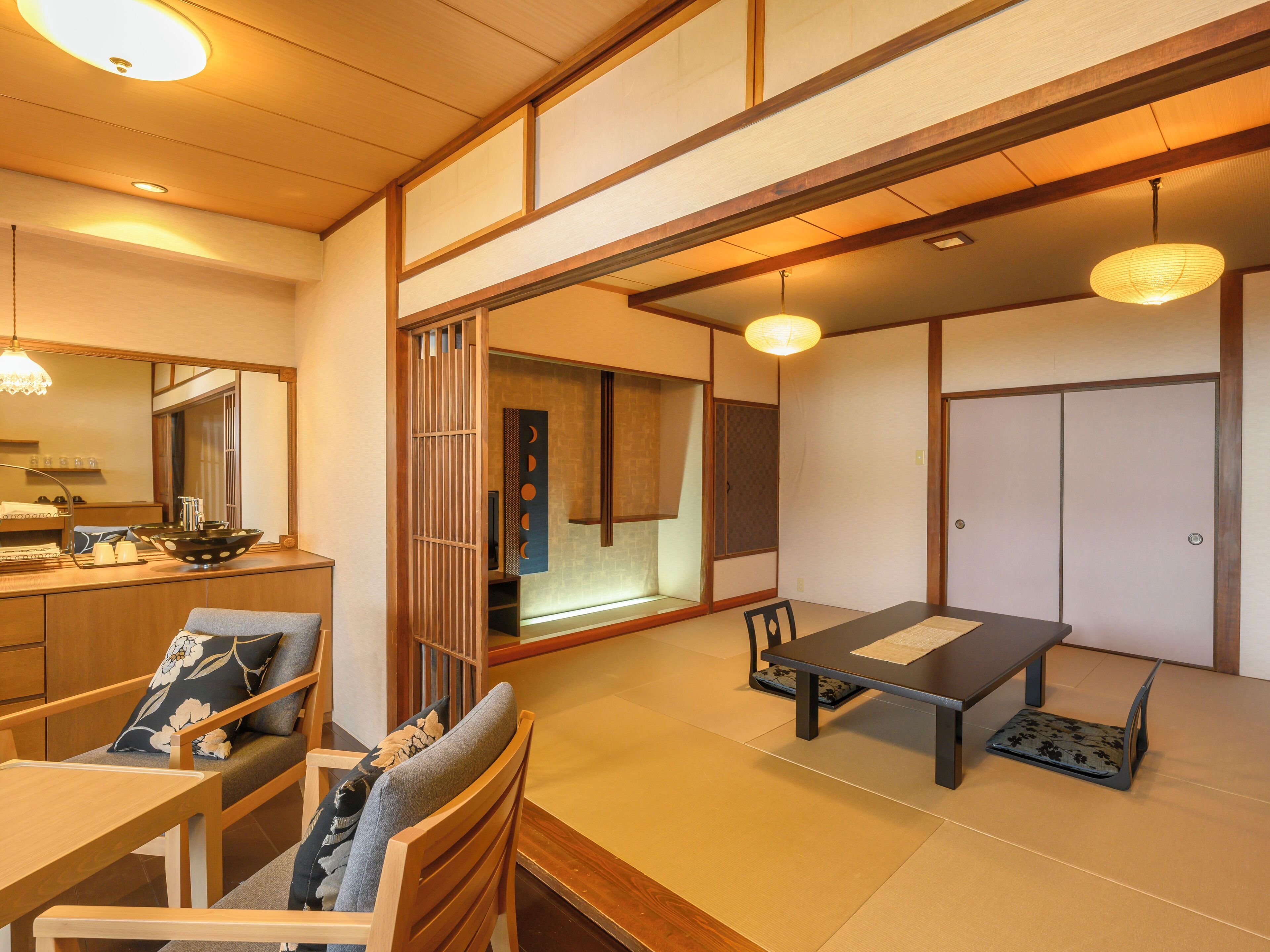 Una habitación tradicional japonesa con suelo de tatami, una mesa baja con banco, un espejo grande y puertas correderas.