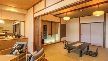Una habitación tradicional japonesa con suelo de tatami, una mesa baja con banco, un espejo grande y puertas correderas.
